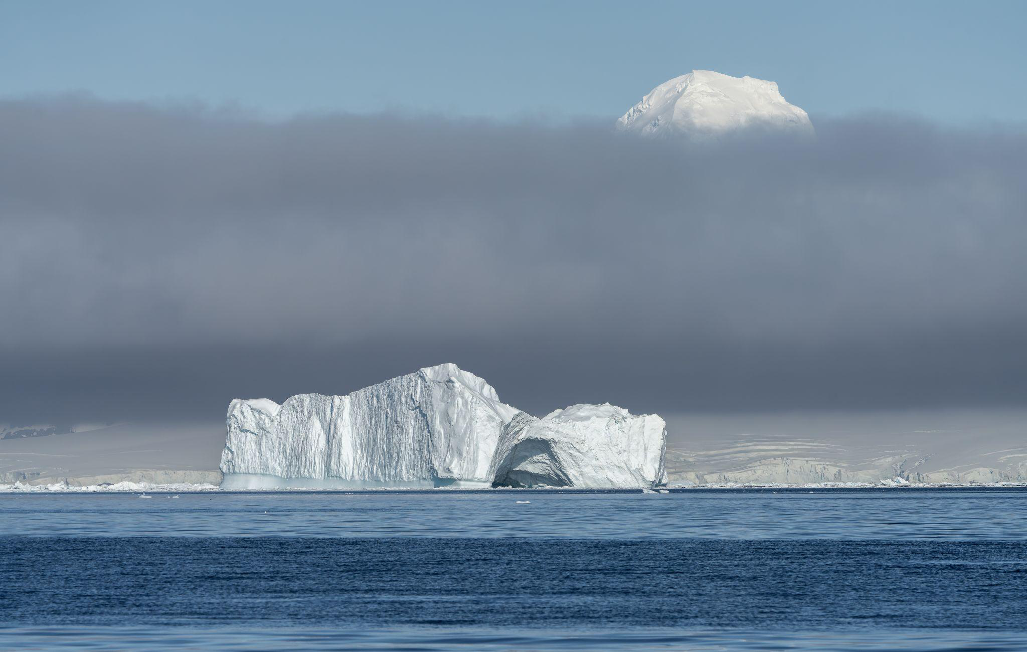 Iceberg, nube y montaña en Antártica