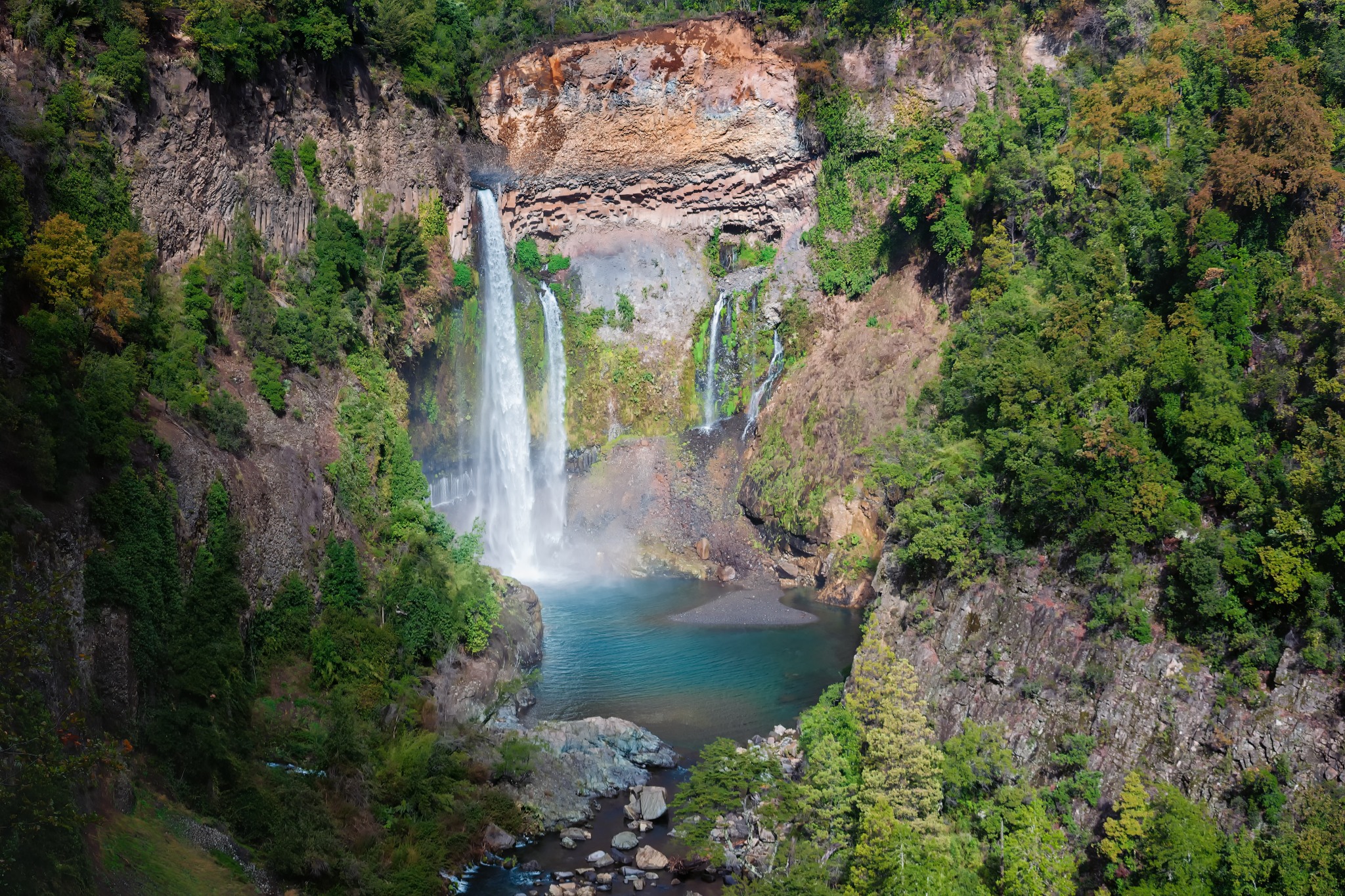 Cascada rodeada de bosque y paredes de roca en Chile