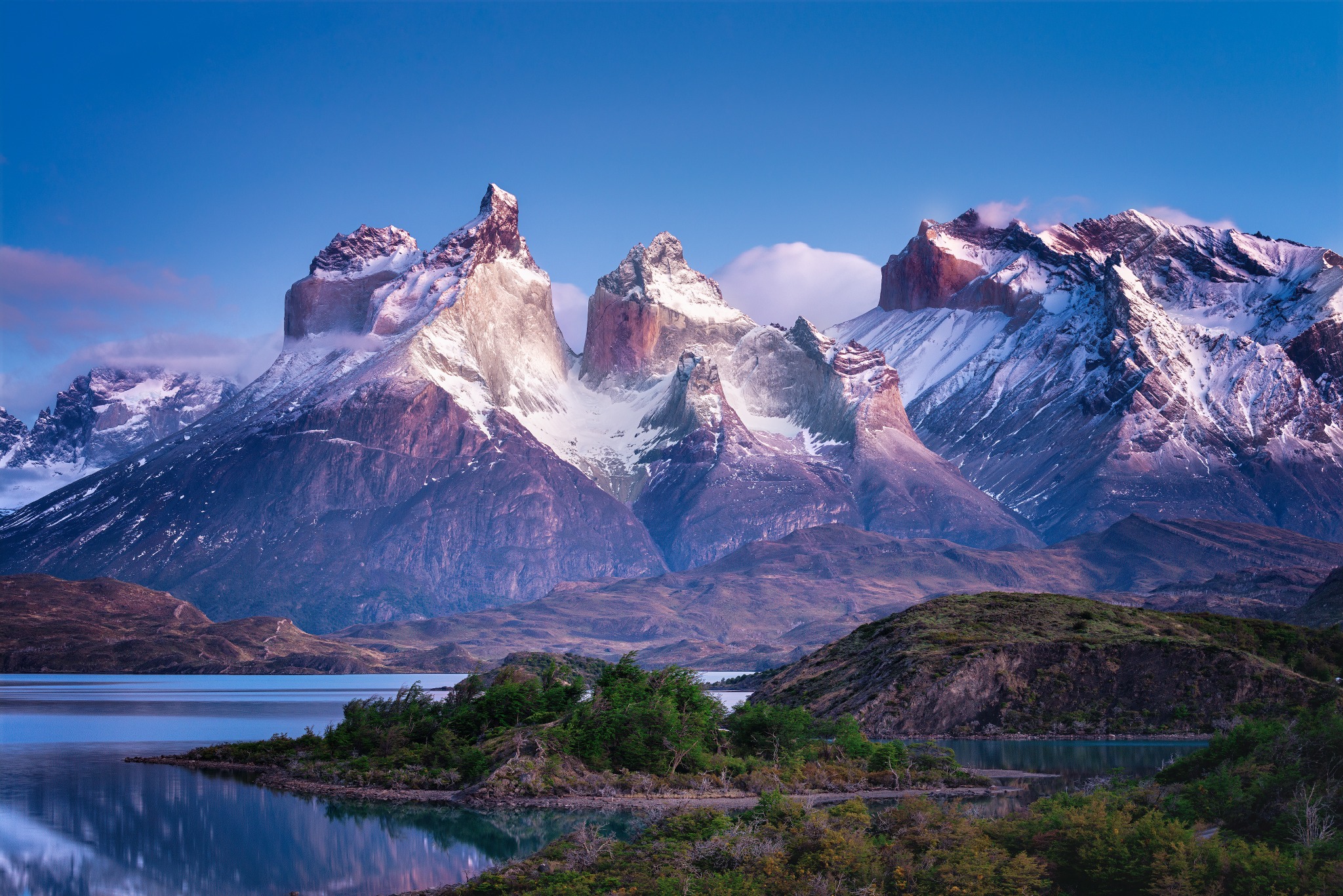 The Cuernos del Paine lit above the lake and forest