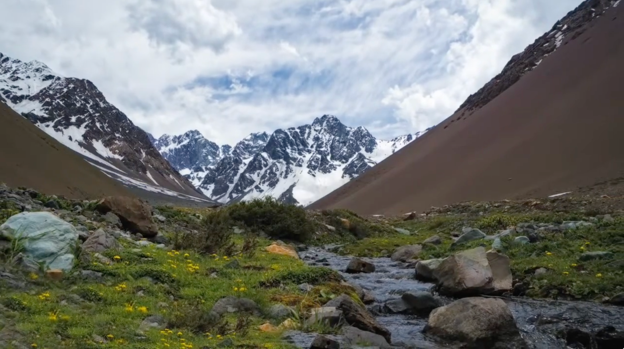 Valle de montaña con cumbres nevadas y un curso de agua